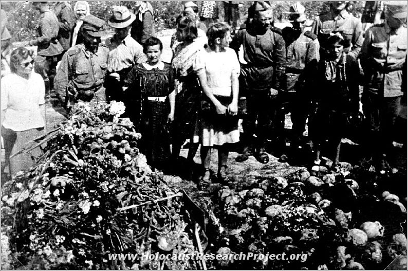 Civilians and military pose behind piles of human remains at Majdanek